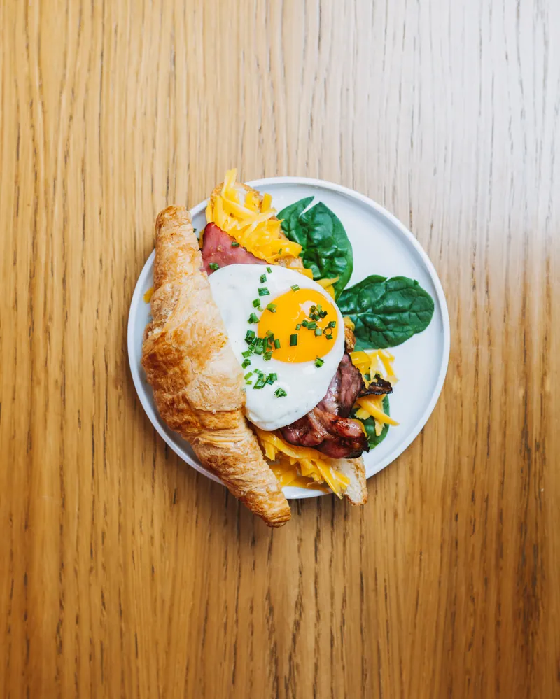 Croissant com ovo estrelado, bacon e queijo cheddar