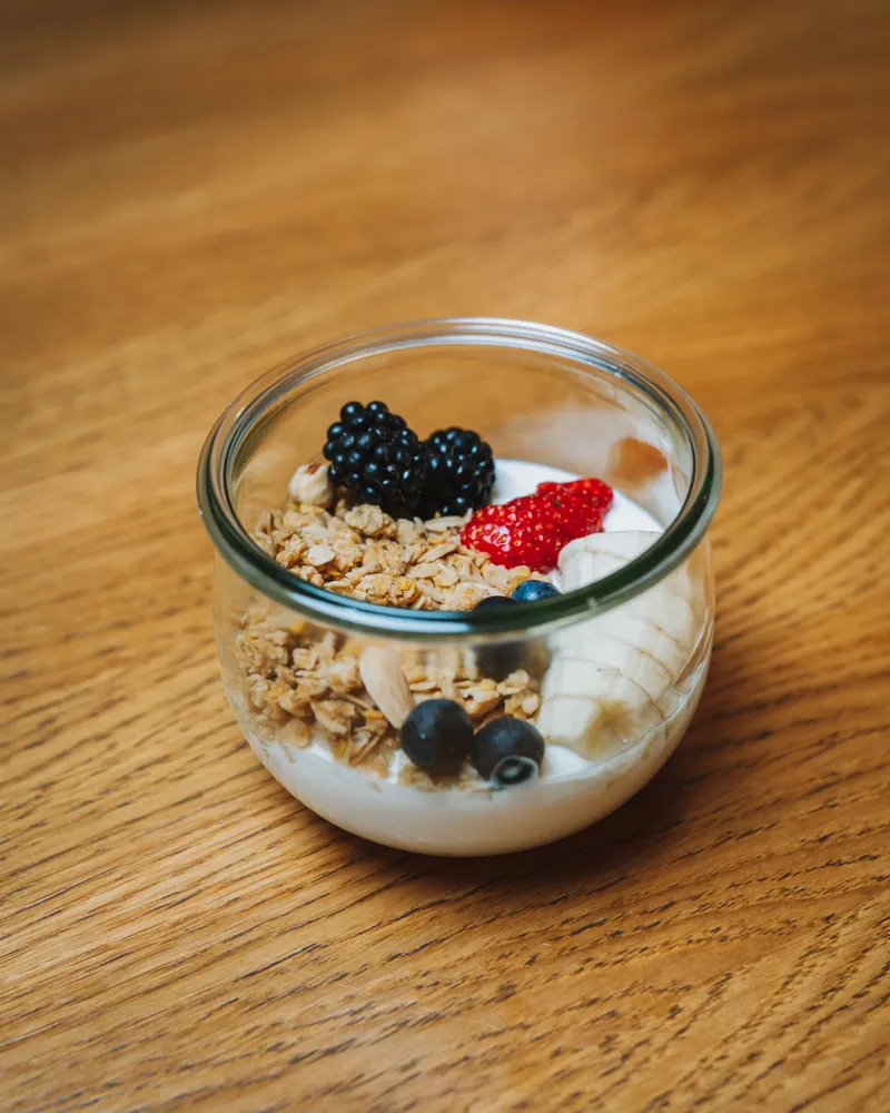 Iogurte com granola, banana e frutos vermelhos em frasco